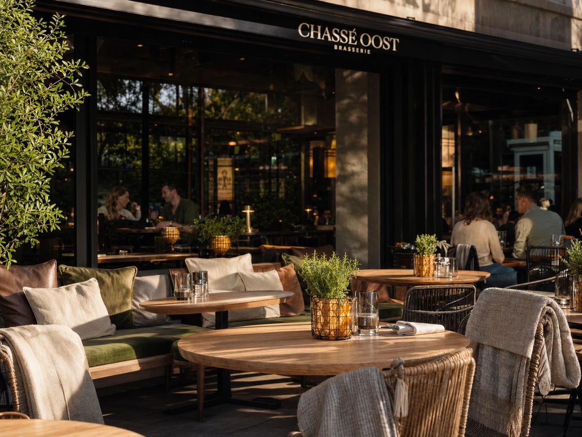 Brasserie gevel met linnen kussens, plantenbakken en avondlicht.
