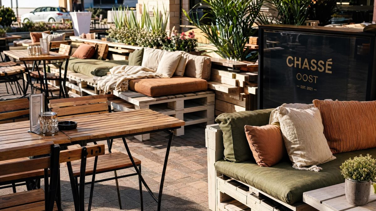 Terras van Brasserie Lenny met houten tafels en groene kussens.