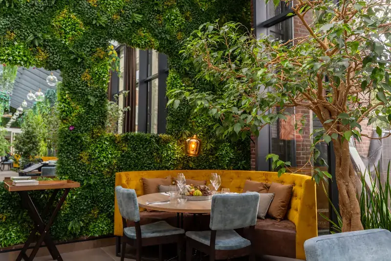 Interieur van Brasserie Lenny in Amsterdam Oost met groene wand, houten tafels en warme verlichting