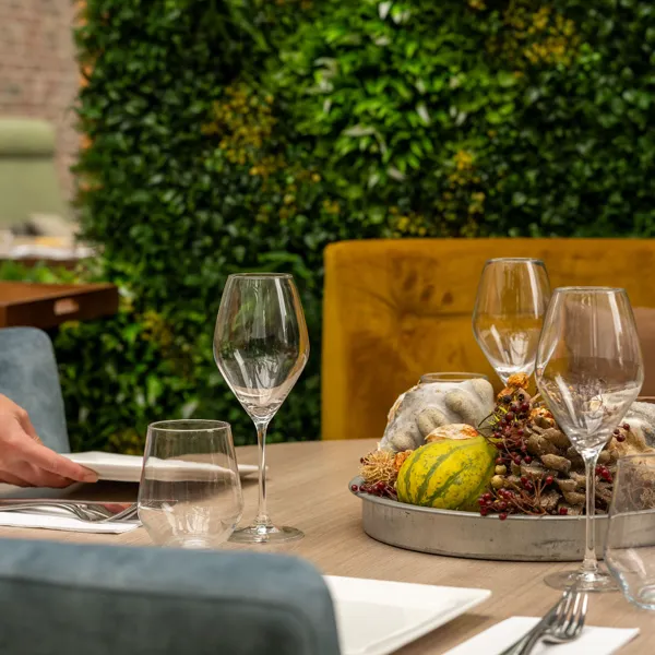Gedekte tafel met groene plantenwand bij Brasserie Lenny in Amsterdam Oost