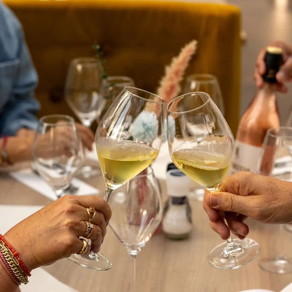 Twee gasten proosten met witte wijn aan tafel in Brasserie Lenny, Amsterdam Oost.