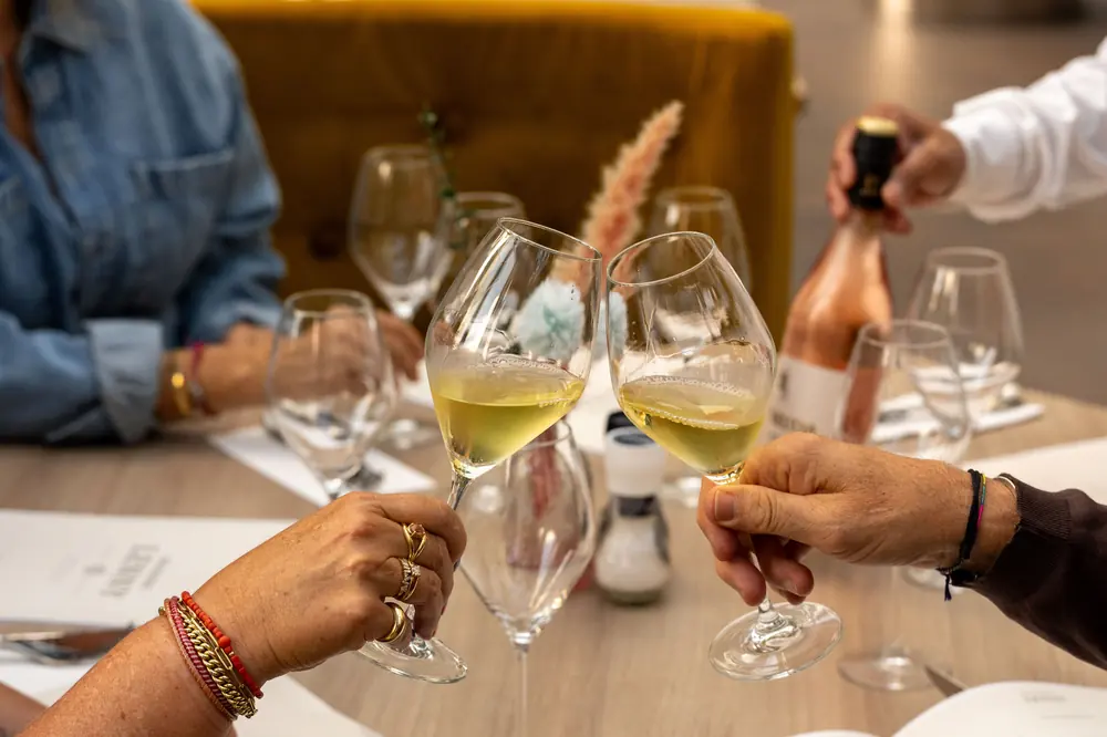 Twee glazen witte wijn worden geproost aan tafel in Brasserie Lenny, Amsterdam Oost.